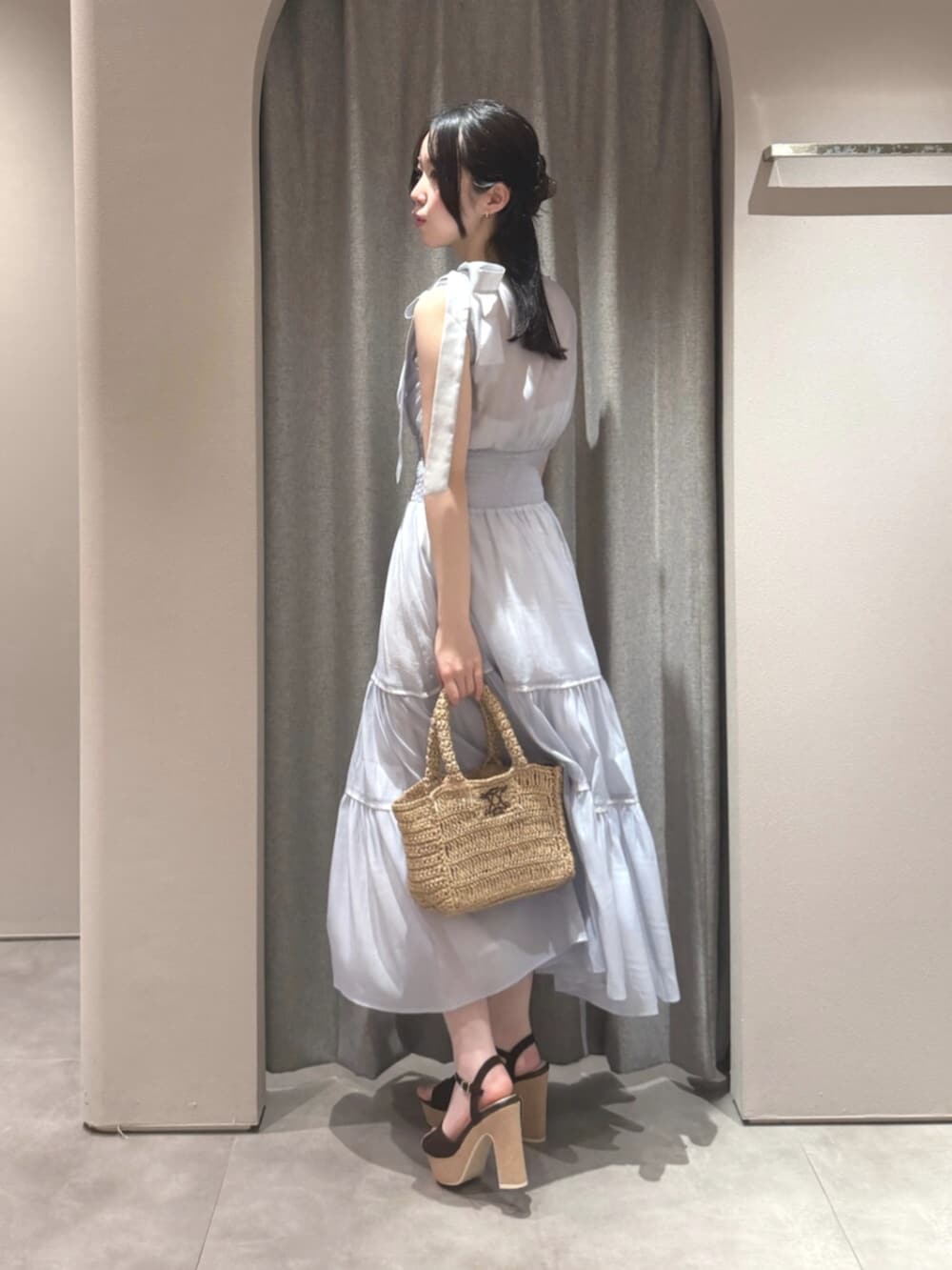 ブラウン系のサンダル、ブルー系のワンピース、ブラウン系のかごバッグを着用したレディースの夏コーディネートの4枚目の写真