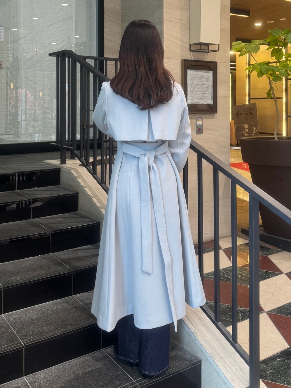 グレー系のトレンチコート、ブルー系のデニムパンツ、ブラック系のブーツを着用したレディースの秋コーディネートの5枚目の写真