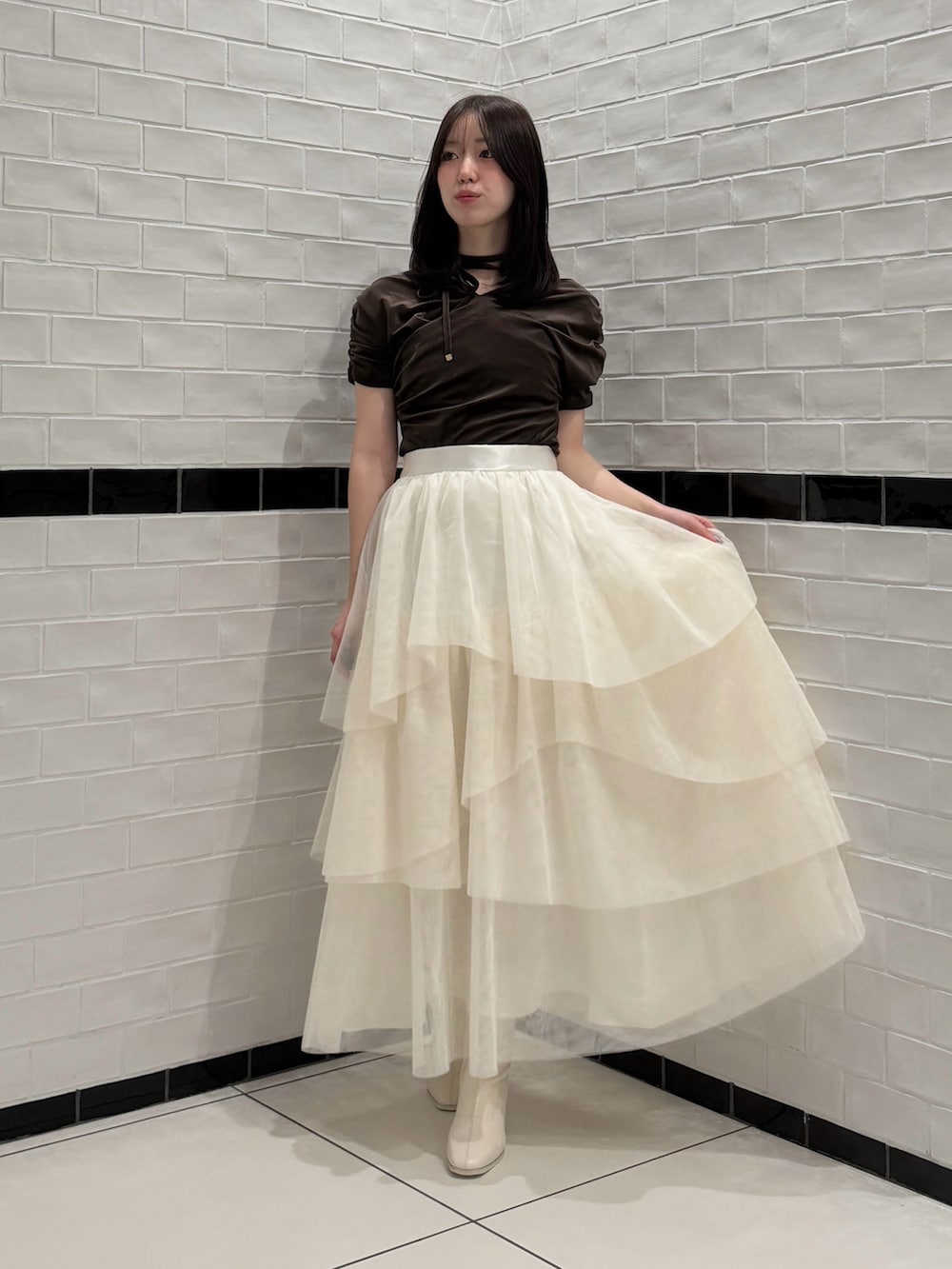 ブラウン系のTシャツ/カットソー、ホワイト系のスカート、ホワイト系のブーツを着用したレディースの秋コーディネートの4枚目の写真