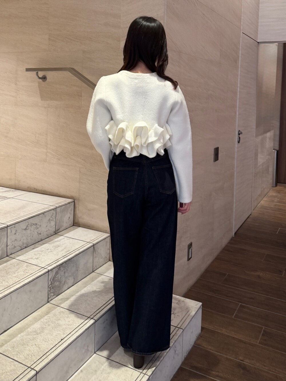 ホワイト系のノーカラージャケット、ブルー系のデニムパンツ、ブラウン系のブーツを着用したレディースの冬コーディネートの5枚目の写真