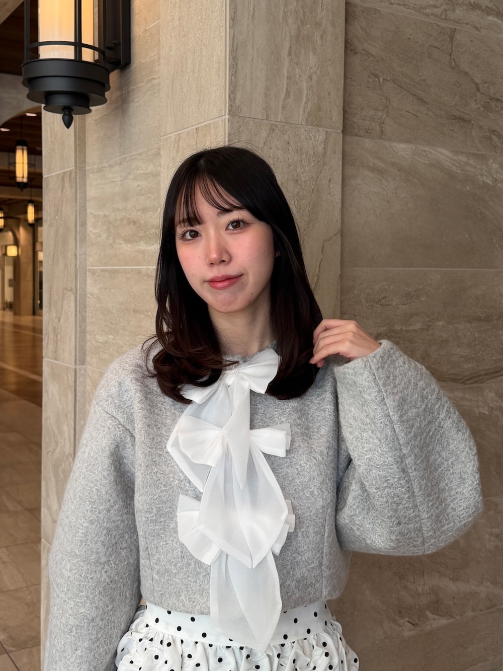 グレー系のブルゾン、ホワイト系のスカート、ブラック系のブーツを着用したレディースの冬コーディネートの6枚目の写真