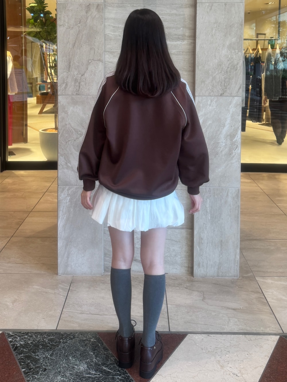 ブラウン系のTシャツ/カットソー、ホワイト系のスカート、ブラウン系のローファーを着用したレディースの秋コーディネートの6枚目の写真