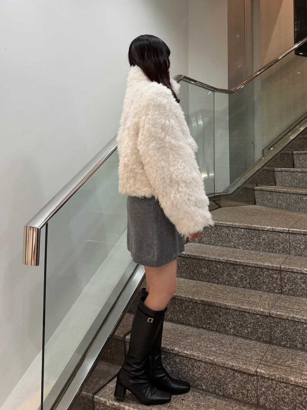 ホワイト系のブルゾン、グレー系のワンピース、ブラック系のブーツを着用したレディースの秋コーディネートの4枚目の写真