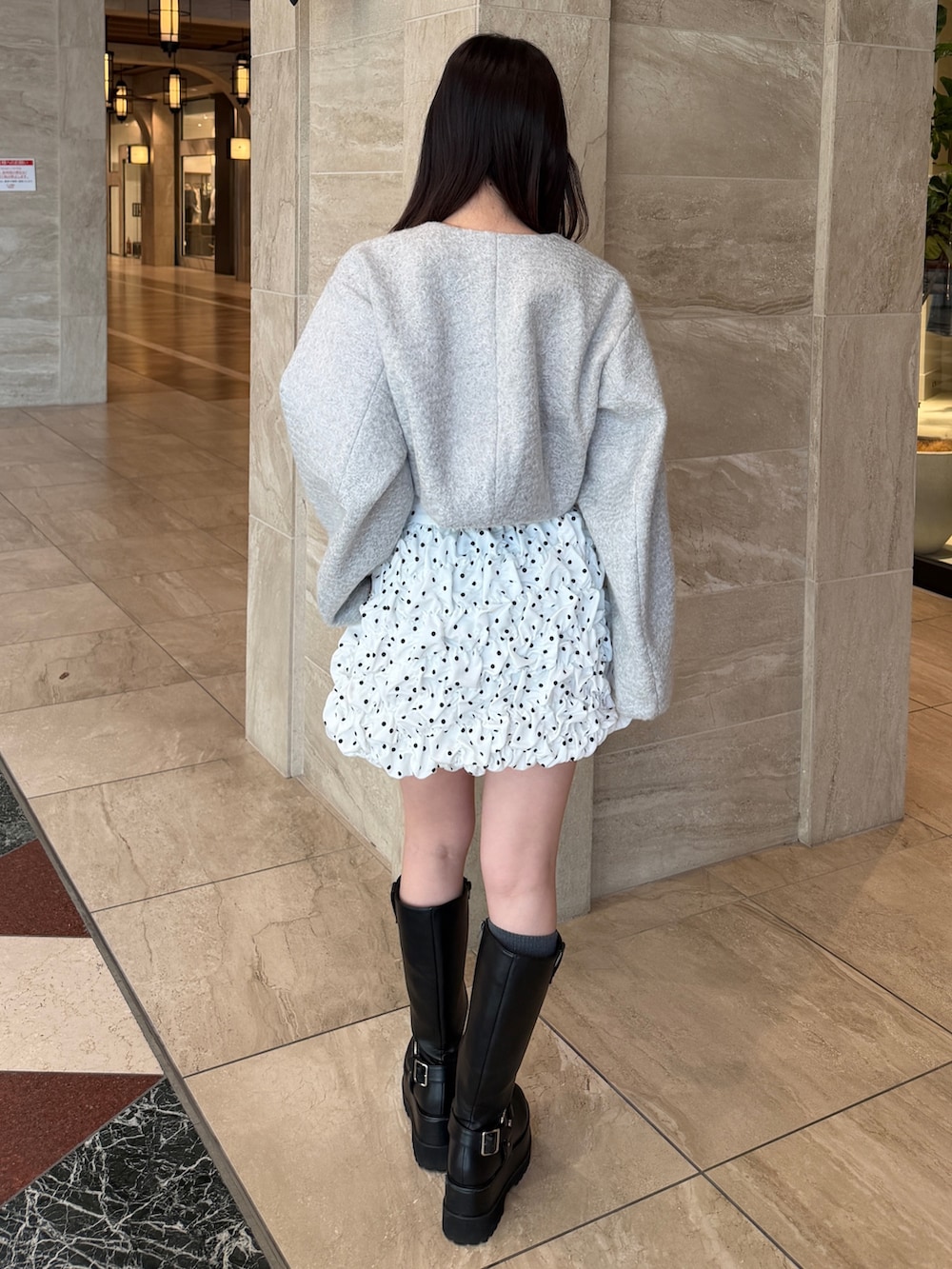 グレー系のブルゾン、ホワイト系のスカート、ブラック系のブーツを着用したレディースの冬コーディネートの5枚目の写真