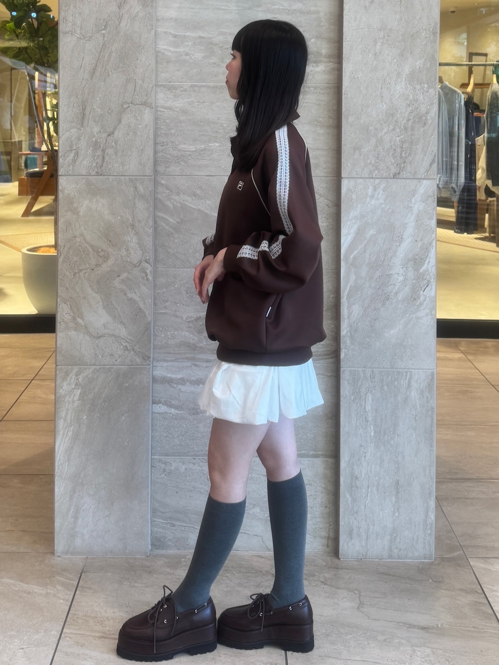 ブラウン系のTシャツ/カットソー、ホワイト系のスカート、ブラウン系のローファーを着用したレディースの秋コーディネートの5枚目の写真