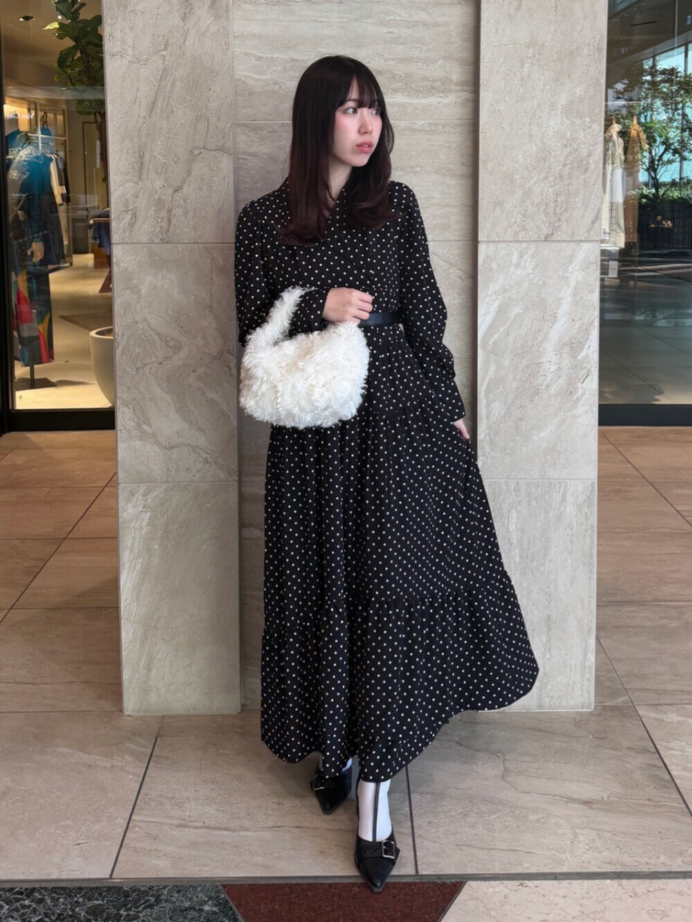 ブラック系のワンピース、ホワイト系のハンドバッグ、ブラック系のパンプスを着用したレディースの秋コーディネートの2枚目の写真