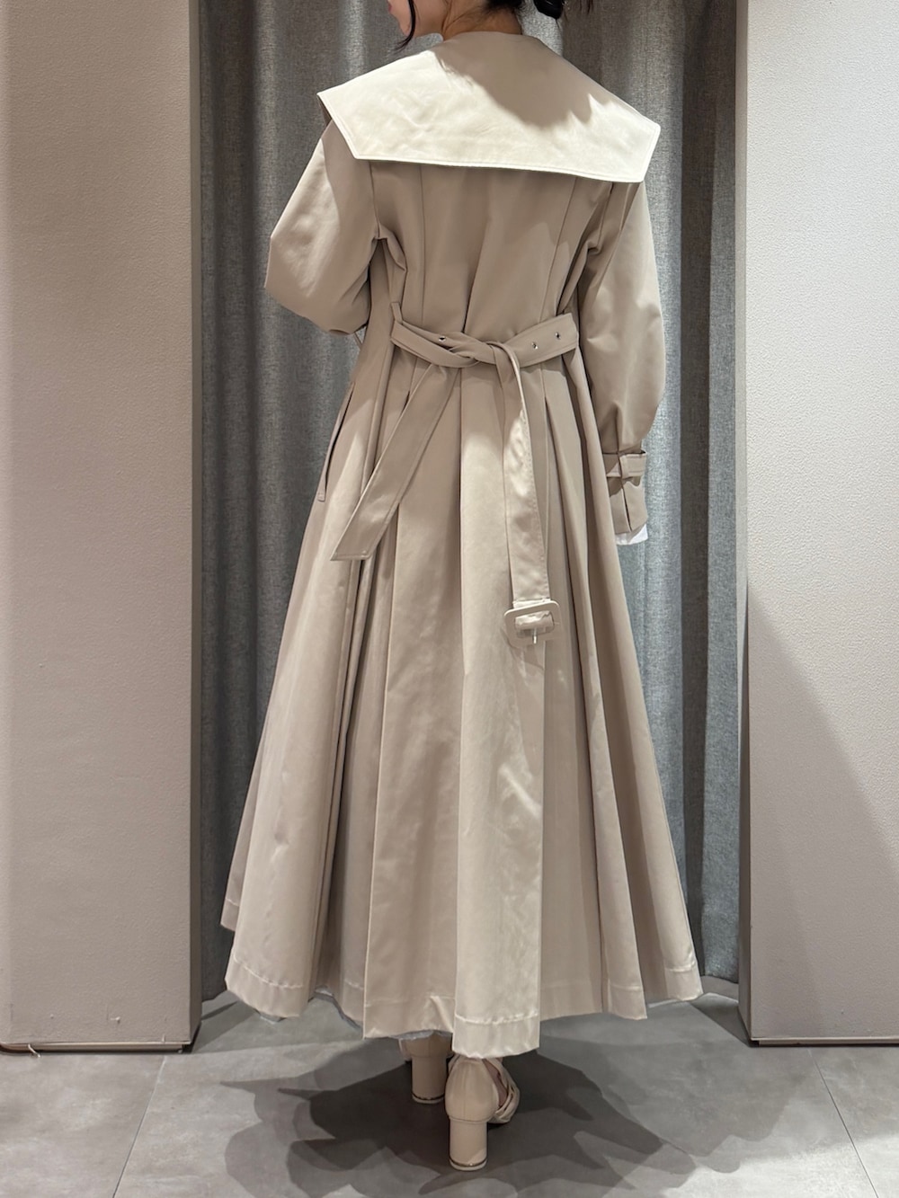 ベージュ系のトレンチコート、ブルー系のドレス、ホワイト系のサンダルを着用したレディースの春コーディネートの3枚目の写真