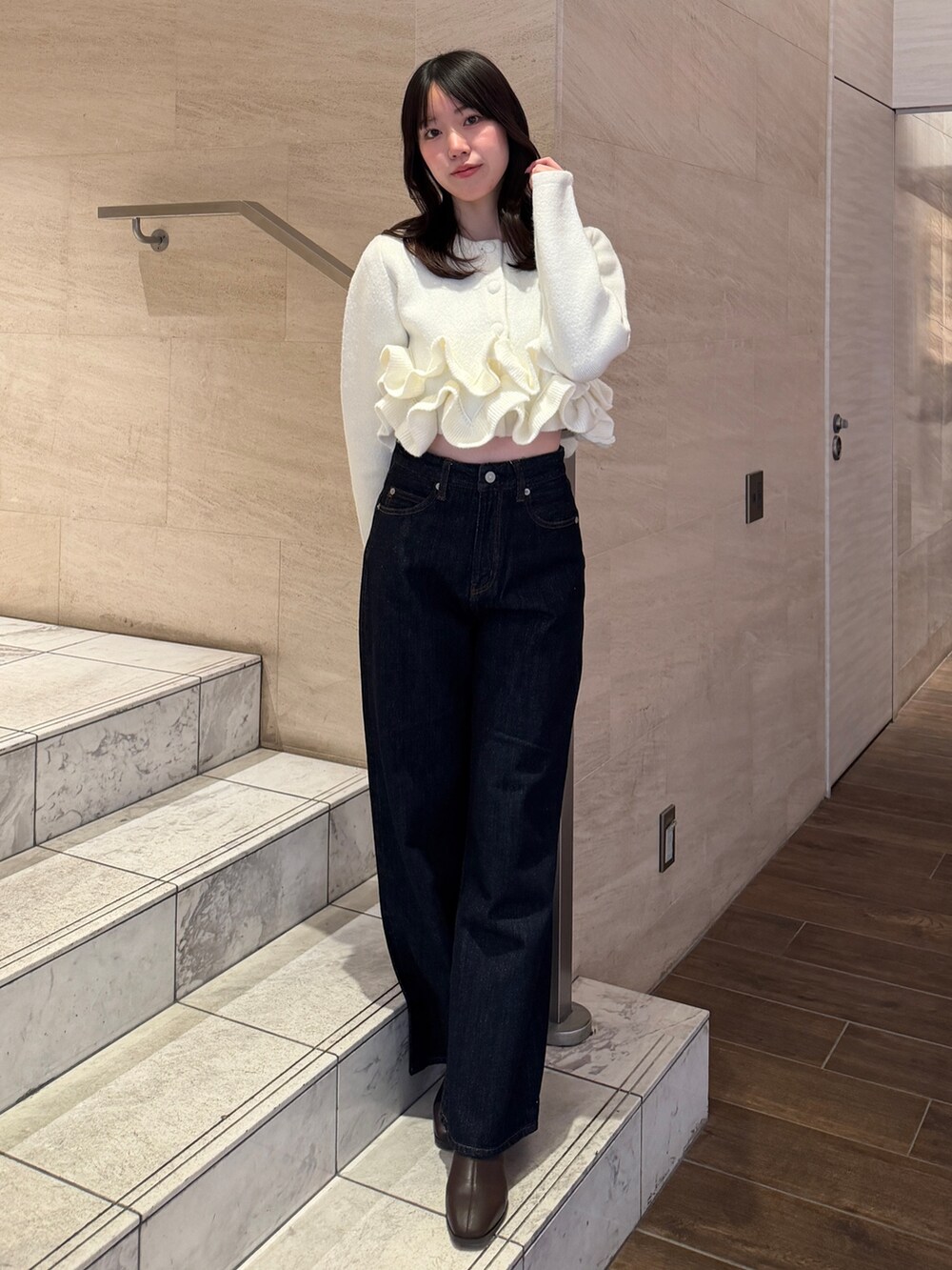 ホワイト系のノーカラージャケット、ブルー系のデニムパンツ、ブラウン系のブーツを着用したレディースの冬コーディネートの2枚目の写真