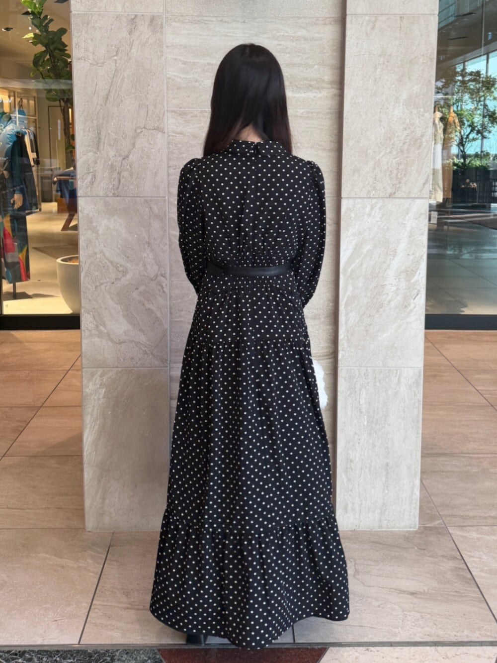 ブラック系のワンピース、ホワイト系のハンドバッグ、ブラック系のパンプスを着用したレディースの秋コーディネートの4枚目の写真