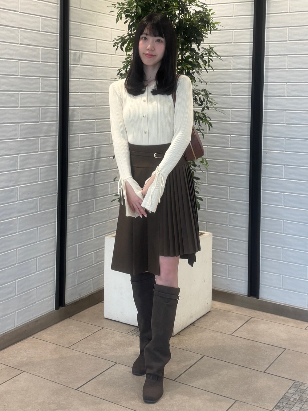ホワイト系のニット/セーター、ブラウン系のスカート、ブラウン系のブーツを着用したレディースの秋コーディネートの2枚目の写真