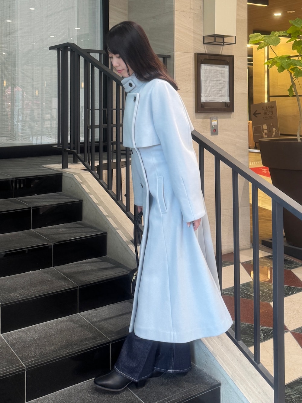 グレー系のトレンチコート、ブルー系のデニムパンツ、ブラック系のブーツを着用したレディースの秋コーディネートの4枚目の写真