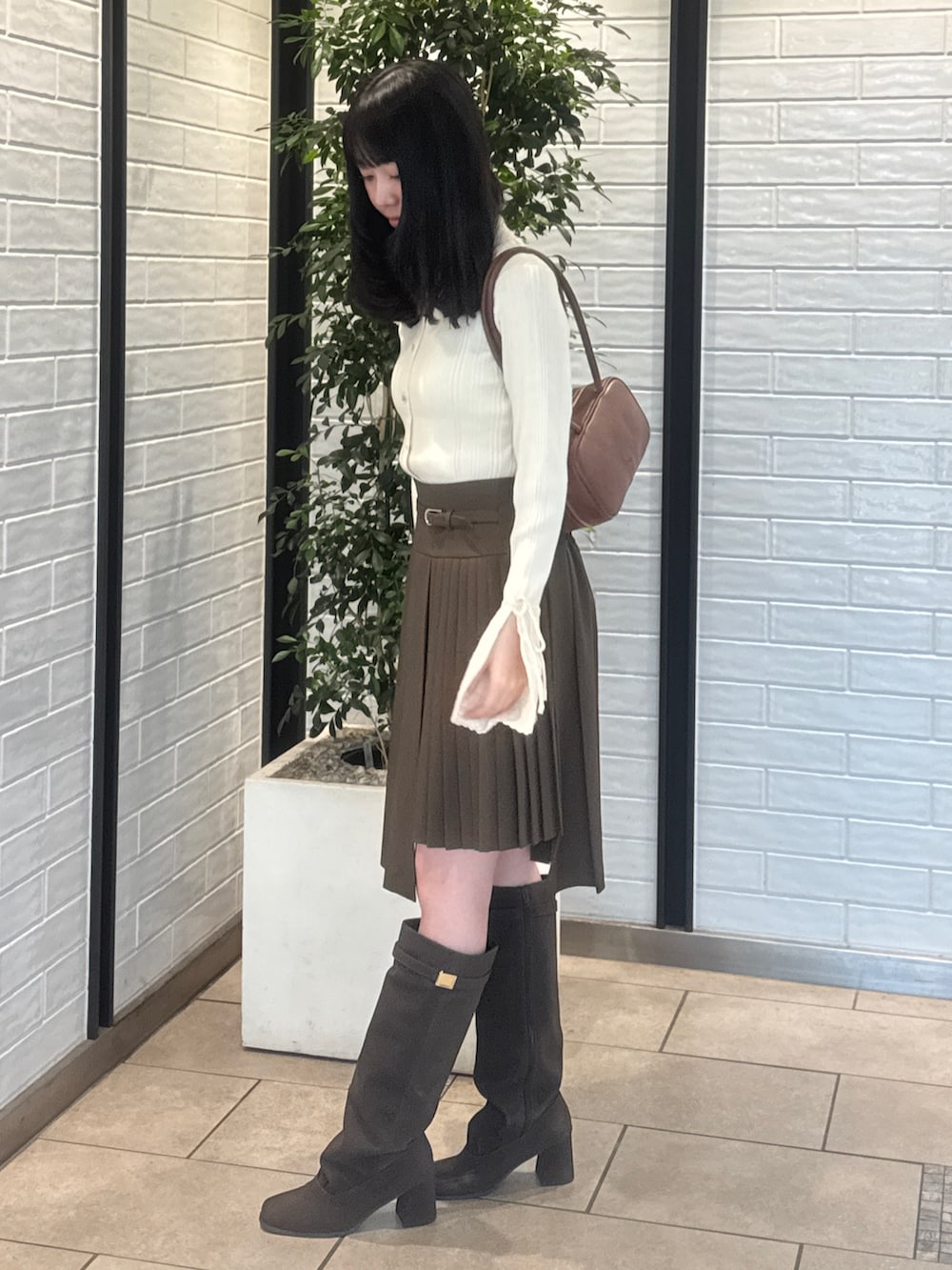 ホワイト系のニット/セーター、ブラウン系のスカート、ブラウン系のブーツを着用したレディースの秋コーディネートの3枚目の写真