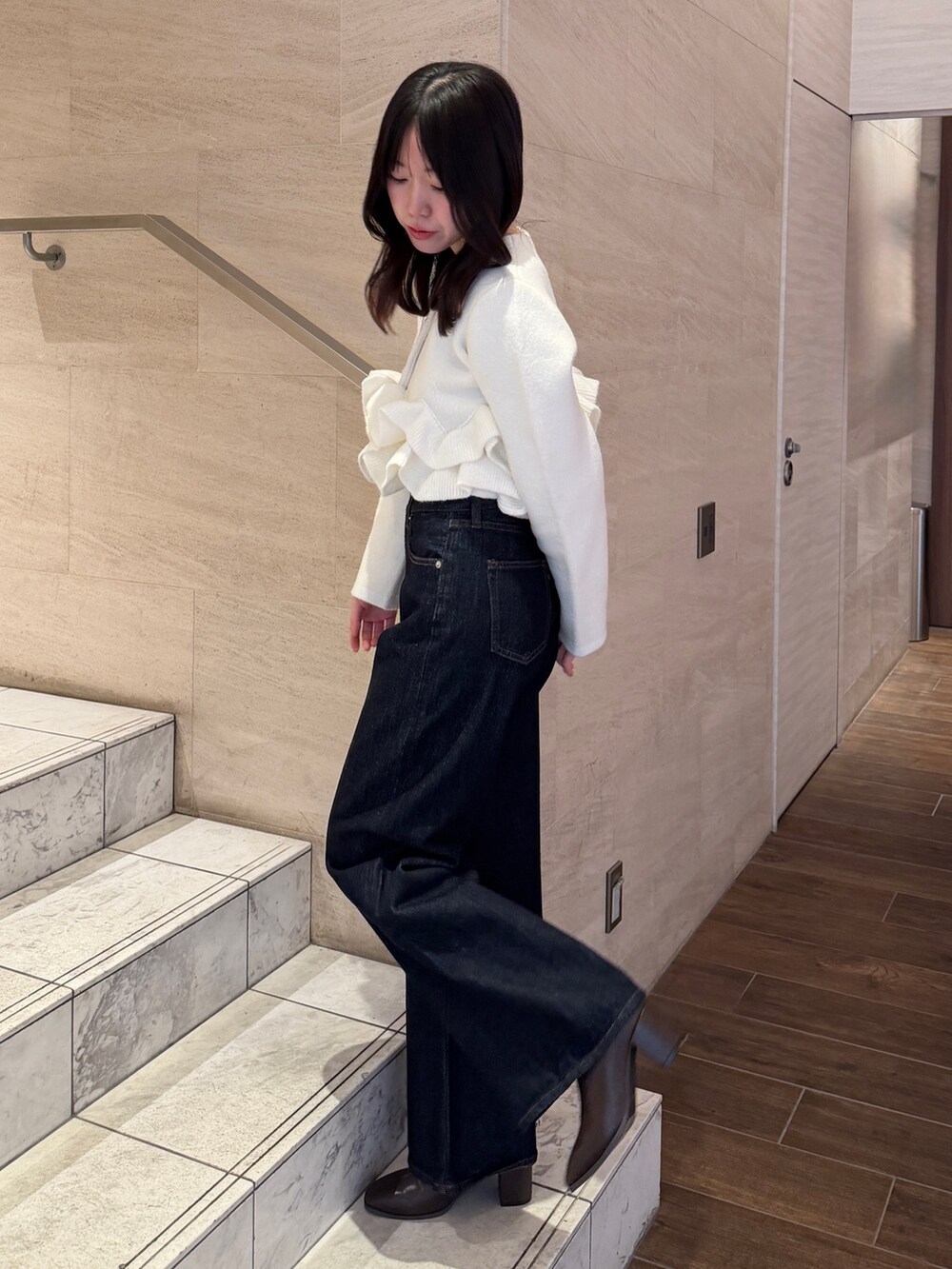 ホワイト系のノーカラージャケット、ブルー系のデニムパンツ、ブラウン系のブーツを着用したレディースの冬コーディネートの4枚目の写真