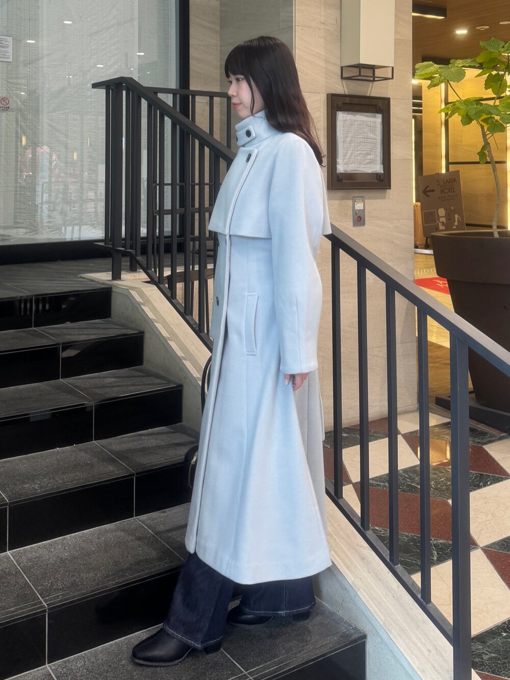 グレー系のトレンチコート、ブルー系のデニムパンツ、ブラック系のブーツを着用したレディースの秋コーディネートの3枚目の写真