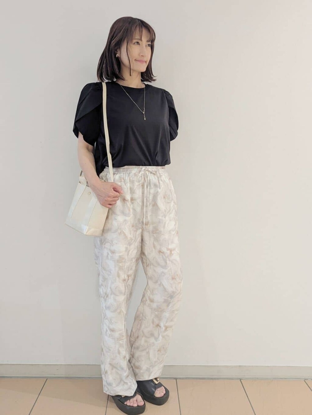 ブラック系のTシャツ/カットソー、グレー系のその他パンツ、ホワイト系のショルダーバッグを着用したレディースの夏コーディネートの2枚目の写真