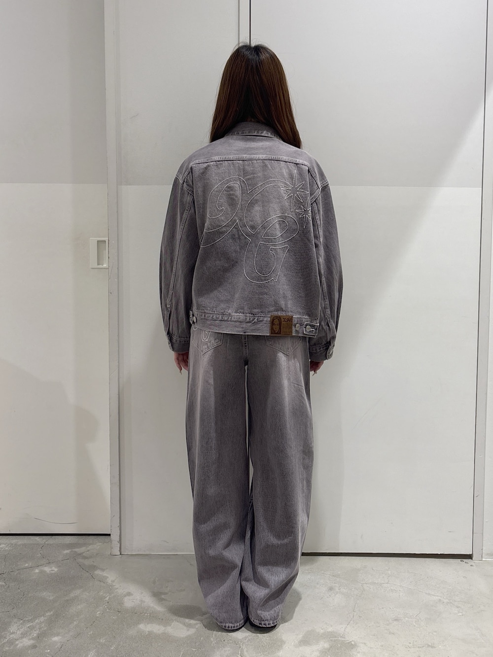 ピンク系のデニムパンツ、ピンク系のデニムジャケット、ブラック系のショルダーバッグを着用したレディースの秋コーディネートの3枚目の写真
