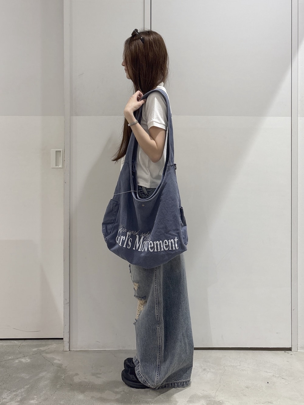 ブルー系のデニムパンツ、ブルー系のショルダーバッグ、ホワイト系のポロシャツを着用したレディースの夏コーディネートの2枚目の写真