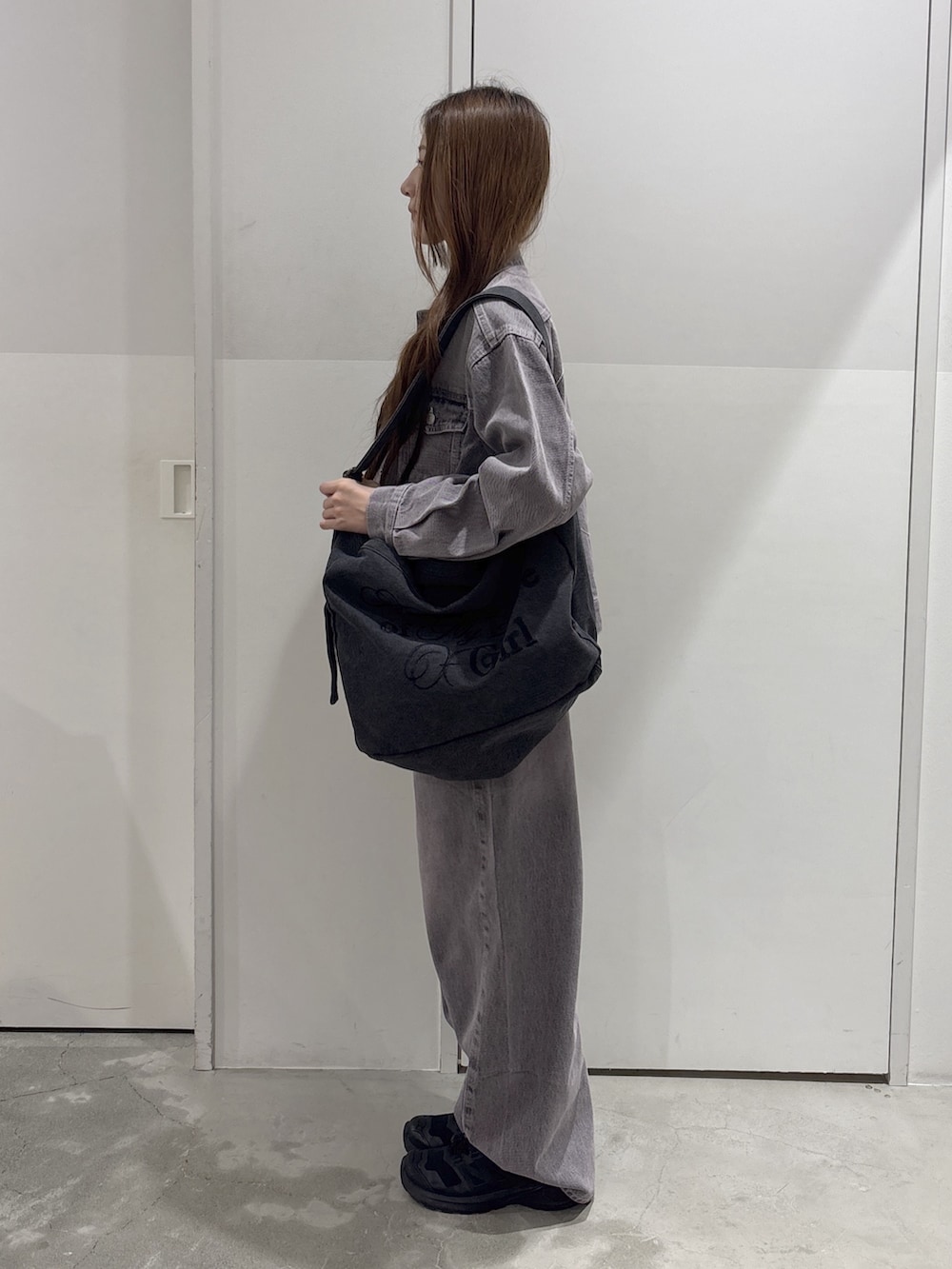 ピンク系のデニムパンツ、ピンク系のデニムジャケット、ブラック系のショルダーバッグを着用したレディースの秋コーディネートの2枚目の写真