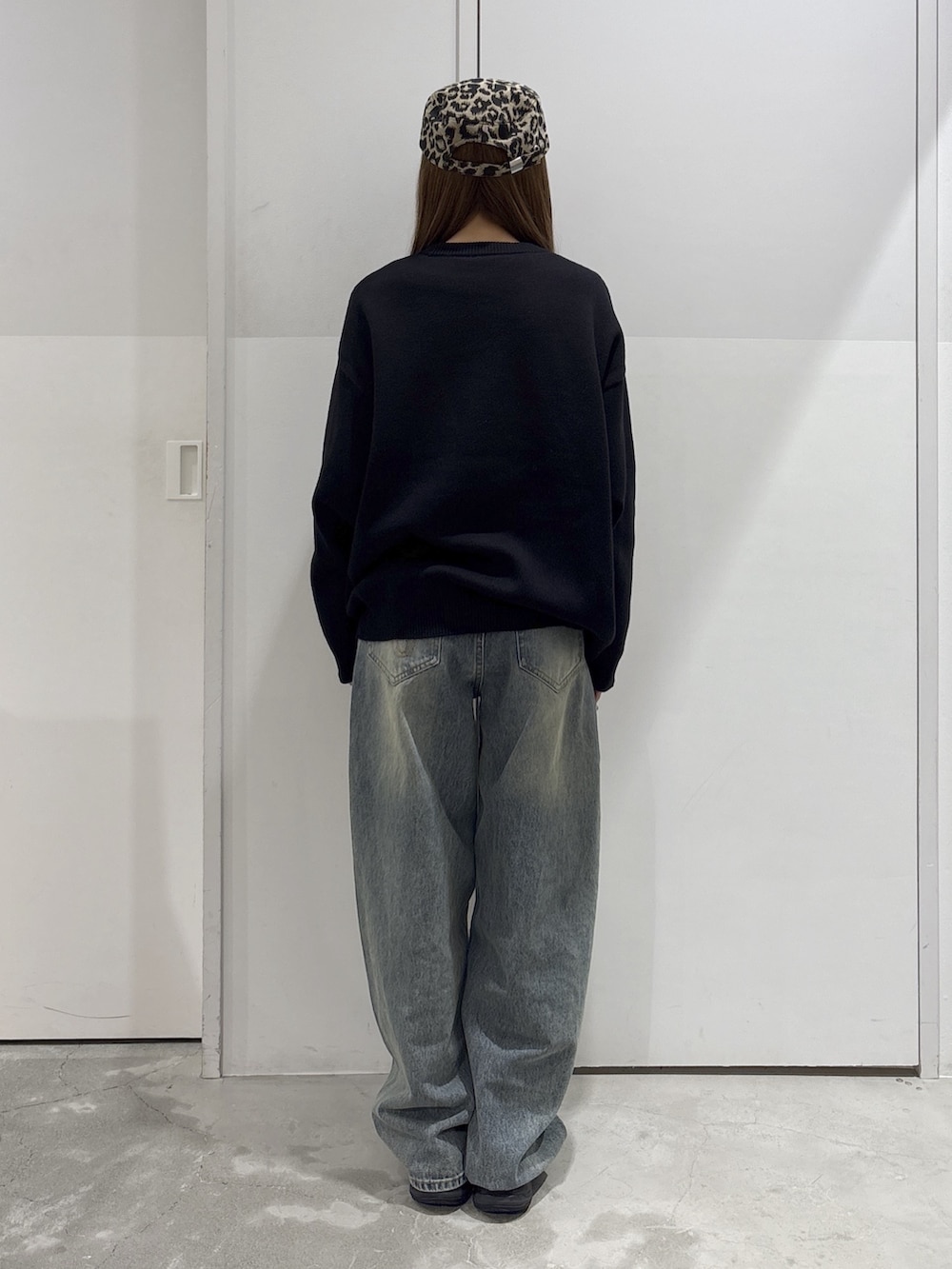 ブルー系のデニムパンツ、ブラック系のニット/セーター、ブラウン系のショルダーバッグを着用したレディースの秋コーディネートの3枚目の写真