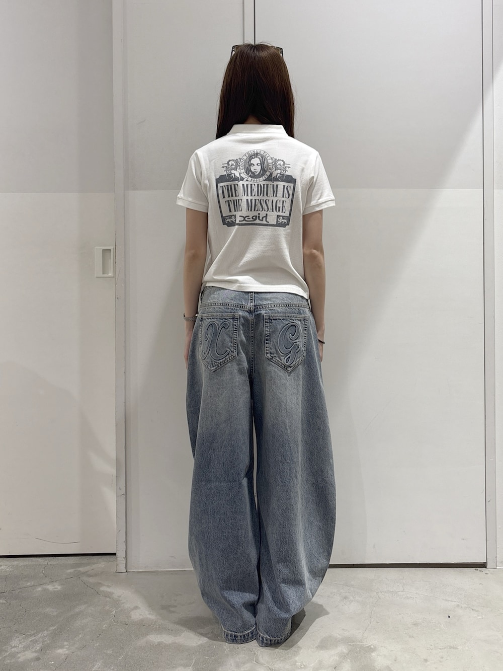 ブルー系のデニムパンツ、ブルー系のショルダーバッグ、ホワイト系のポロシャツを着用したレディースの夏コーディネートの3枚目の写真
