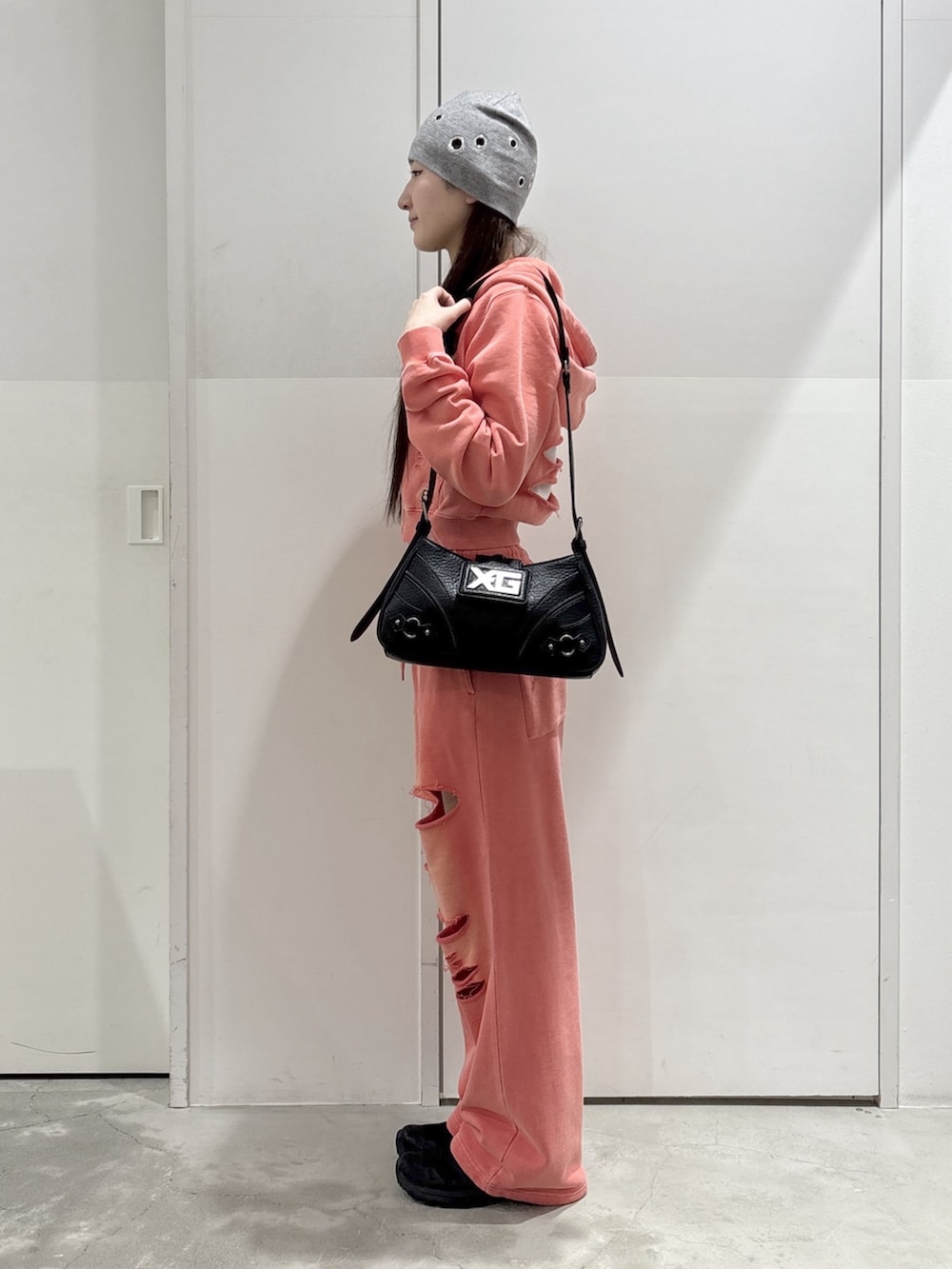 オレンジ系のパーカー、オレンジ系のスウェットパンツ、ブラック系のショルダーバッグを着用したレディースの春コーディネートの2枚目の写真