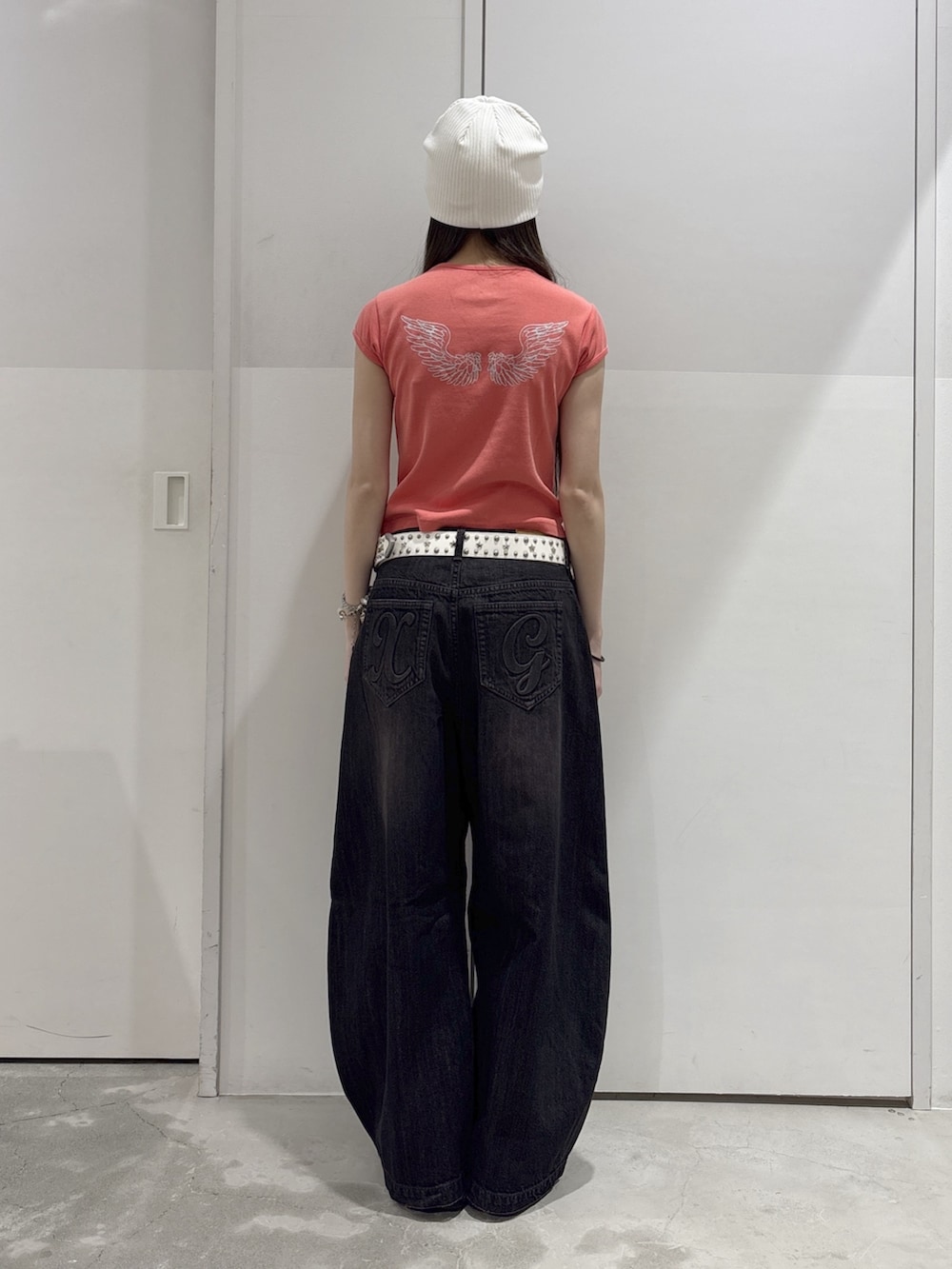 ブラック系のデニムパンツ、オレンジ系のTシャツ/カットソー、ブラック系のハンドバッグを着用したレディースの夏コーディネートの3枚目の写真