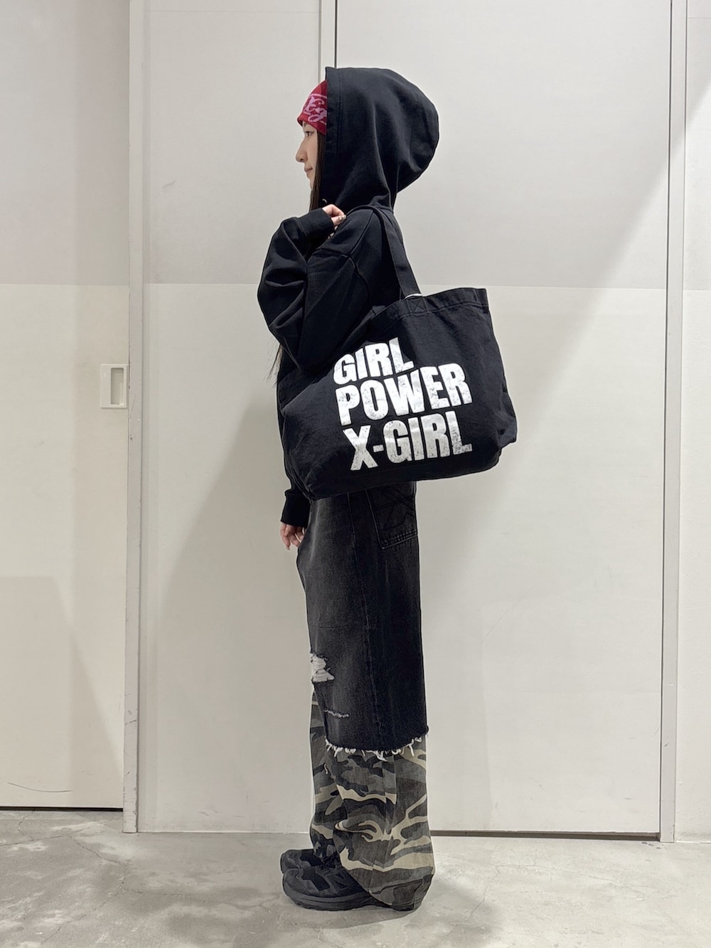 ブラック系のパーカー、ブラック系のトートバッグ、ブラック系のデニムパンツを着用したレディースの春コーディネートの2枚目の写真