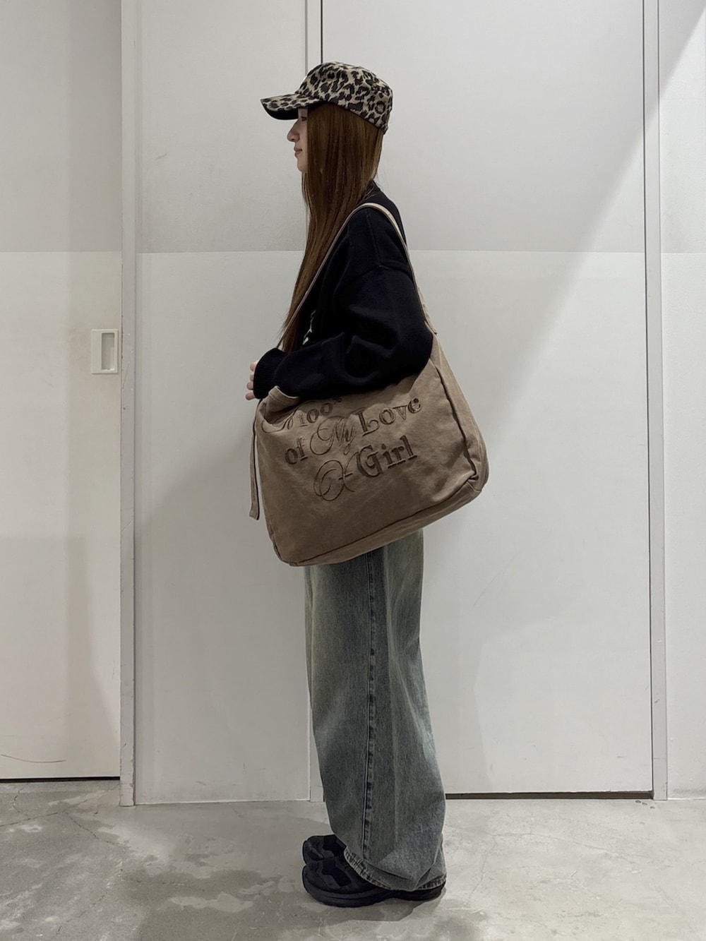 ブルー系のデニムパンツ、ブラック系のニット/セーター、ブラウン系のショルダーバッグを着用したレディースの秋コーディネートの2枚目の写真