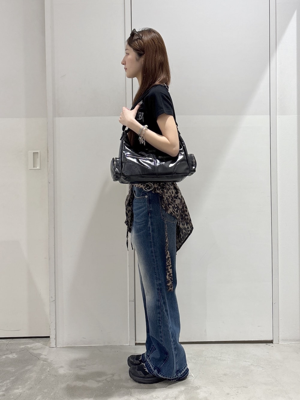 ブルー系のデニムパンツ、ブラック系のTシャツ/カットソー、ブラック系のショルダーバッグを着用したレディースの夏コーディネートの2枚目の写真