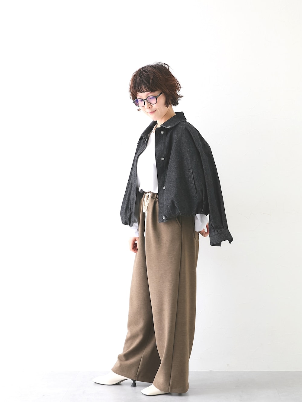 ブラウン系のパンツ、ホワイト系のTシャツ/カットソー、ブラック系のカバーオールを着用したレディースの秋コーディネートの2枚目の写真