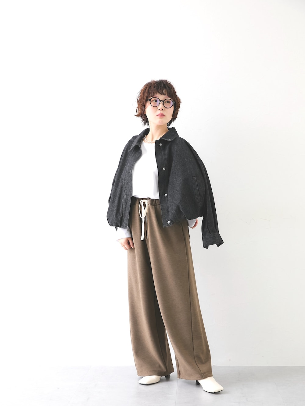 ブラウン系のパンツ、ホワイト系のTシャツ/カットソー、ブラック系のカバーオールを着用したレディースの秋コーディネートの3枚目の写真
