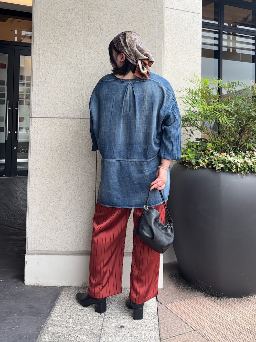 ブラック系のトートバッグ、オレンジ系のその他パンツ、ブルー系のシャツ/ブラウスを着用したレディースの秋コーディネートの3枚目の写真