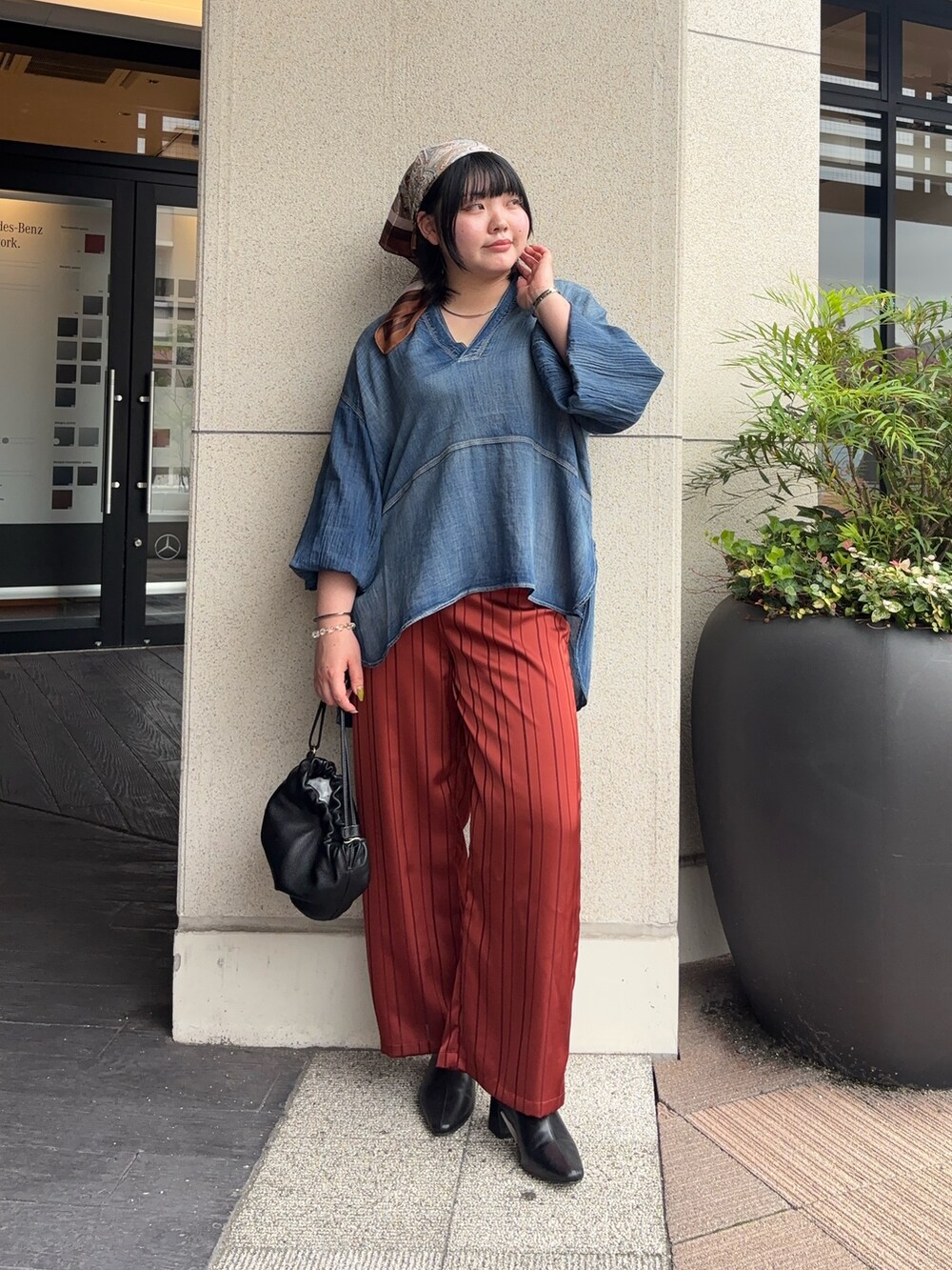 ブラック系のトートバッグ、オレンジ系のその他パンツ、ブルー系のシャツ/ブラウスを着用したレディースの秋コーディネートの2枚目の写真