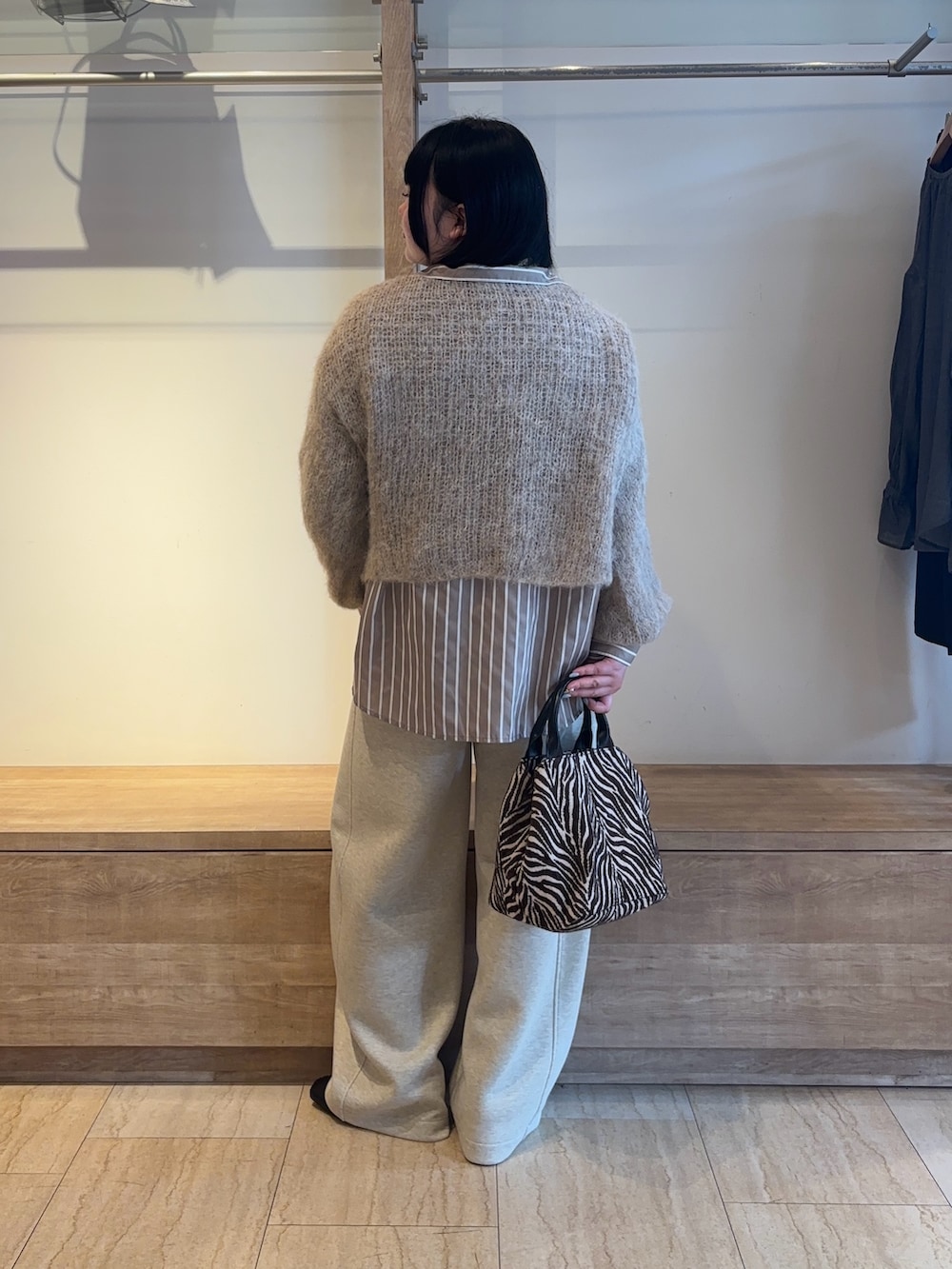 ベージュ系のニット/セーター、ブラウン系のシャツ/ブラウス、ブラウン系のトートバッグを着用したレディースの秋コーディネートの2枚目の写真