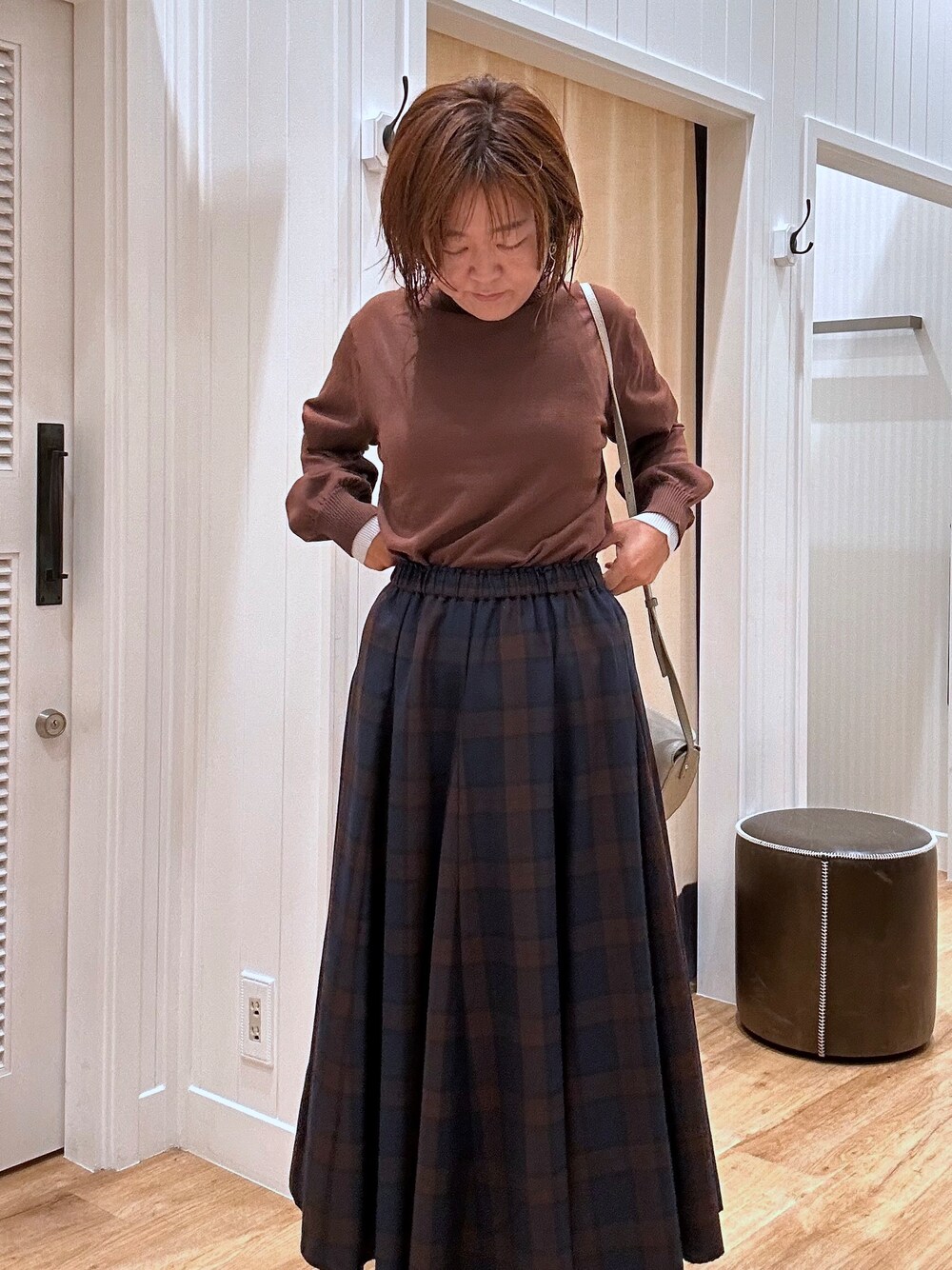 ブルー系のスカート、ブラウン系のニット/セーター、ブラック系のパンプスを着用したレディースの秋コーディネートの9枚目の写真