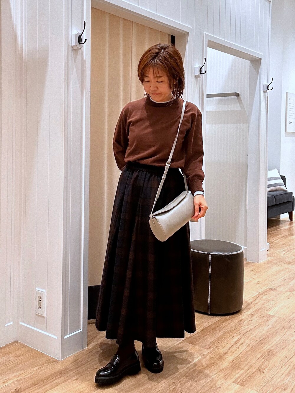 ブルー系のスカート、ブラウン系のニット/セーター、ブラック系のパンプスを着用したレディースの秋コーディネートの6枚目の写真