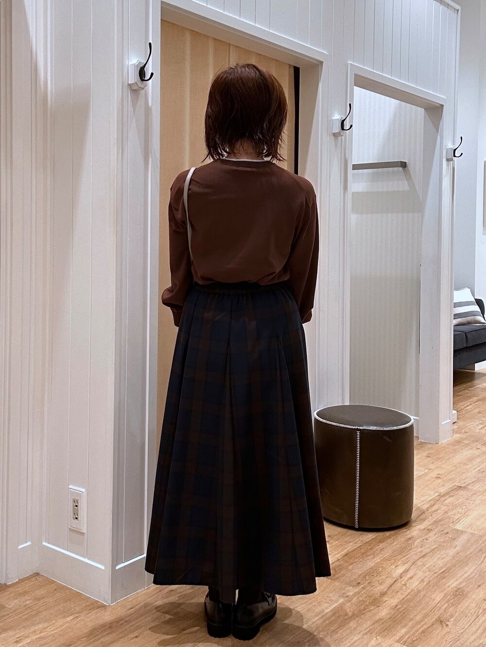 ブルー系のスカート、ブラウン系のニット/セーター、ブラック系のパンプスを着用したレディースの秋コーディネートの8枚目の写真