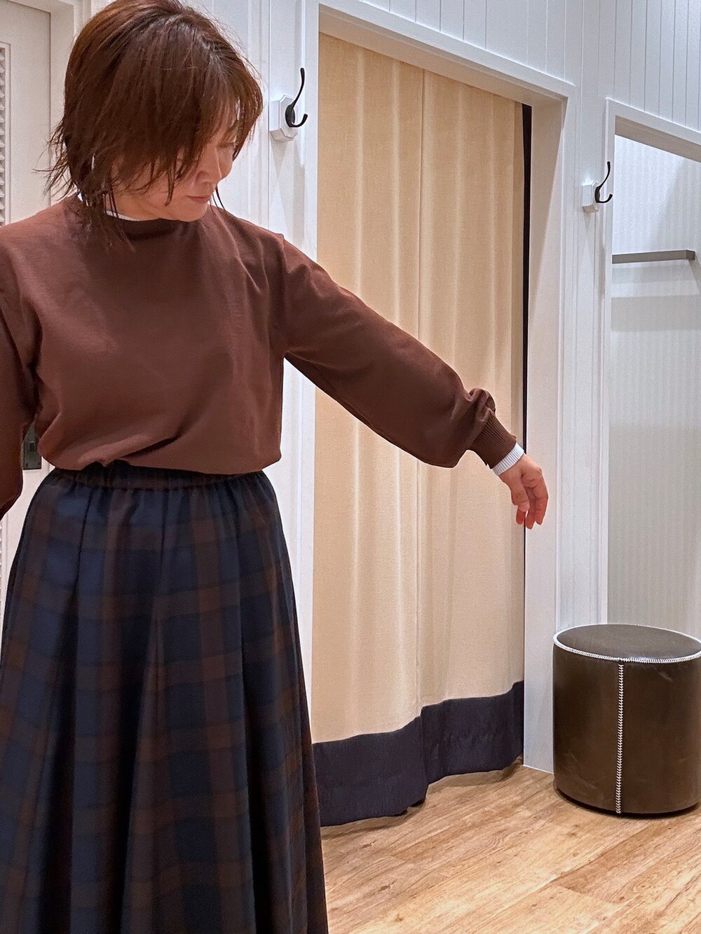 ブルー系のスカート、ブラウン系のニット/セーター、ブラック系のパンプスを着用したレディースの秋コーディネートの10枚目の写真