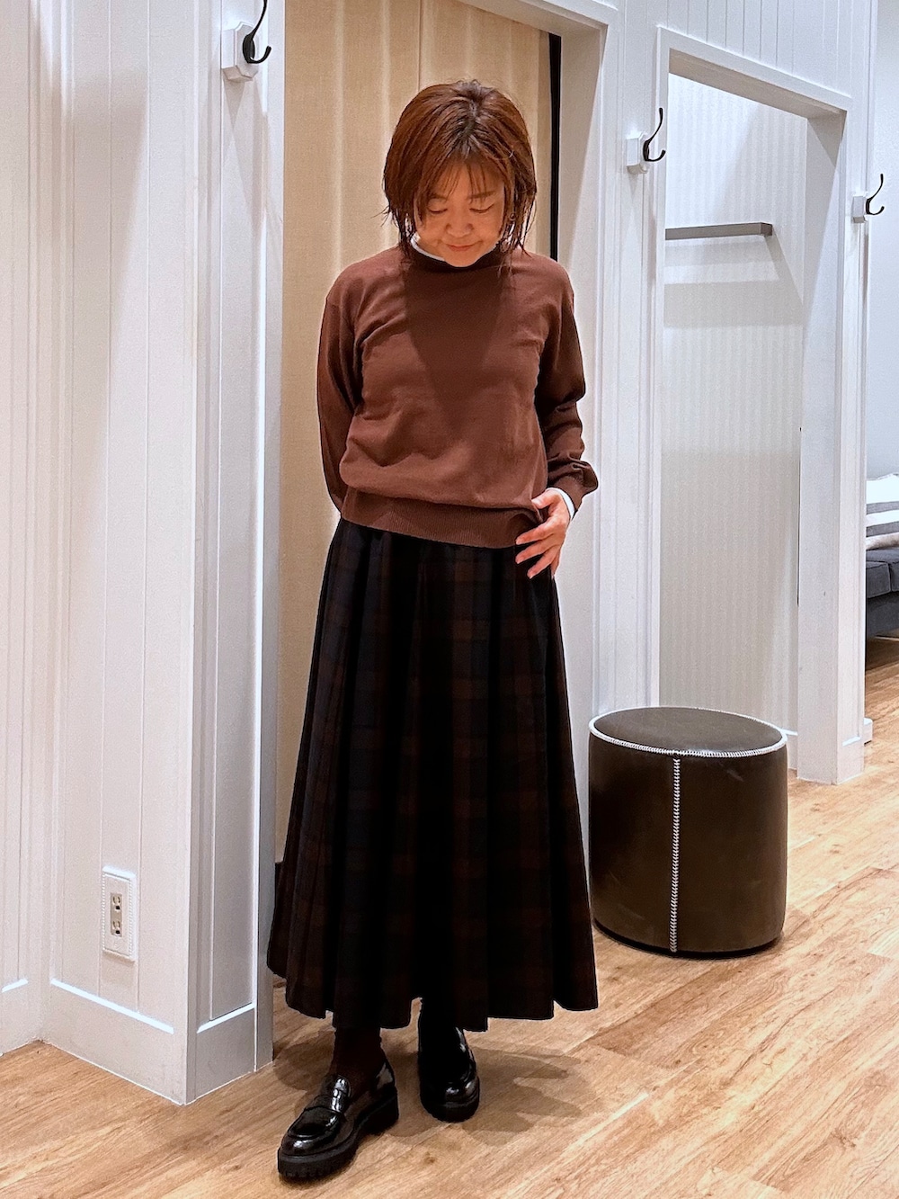 ブルー系のスカート、ブラウン系のニット/セーター、ブラック系のパンプスを着用したレディースの秋コーディネートの2枚目の写真
