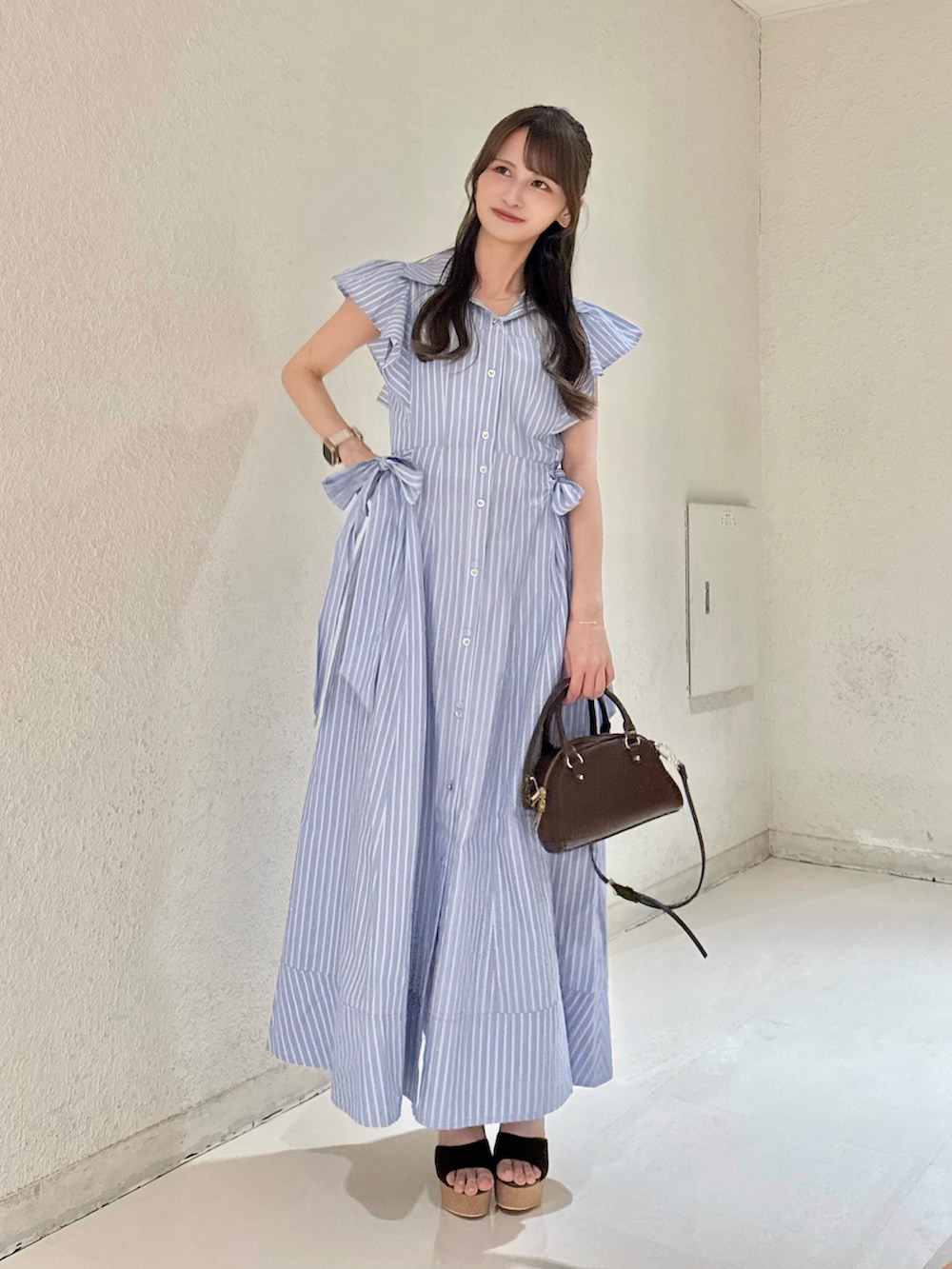 ブルー系のワンピース、ブラウン系のハンドバッグ、ブラウン系のサンダルを着用したレディースの夏コーディネートの2枚目の写真