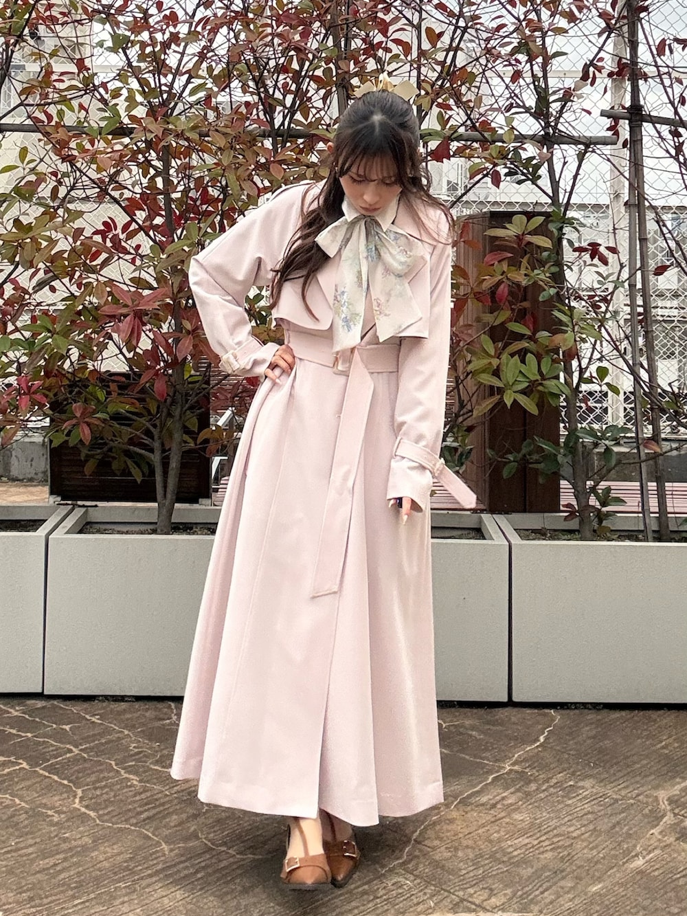 ピンク系のトレンチコート、ブラウン系のパンプスを着用したレディースの冬コーディネートの2枚目の写真