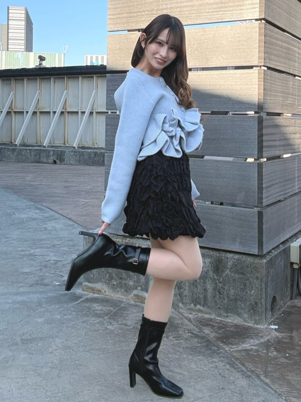 ブルー系のノーカラージャケット、ブラック系のスカート、ブラック系のブーツを着用したレディースの冬コーディネートの3枚目の写真