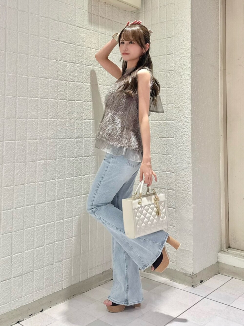 ブルー系のデニムパンツ、グレー系のタンクトップ、ホワイト系のハンドバッグを着用したレディースの夏コーディネートの2枚目の写真