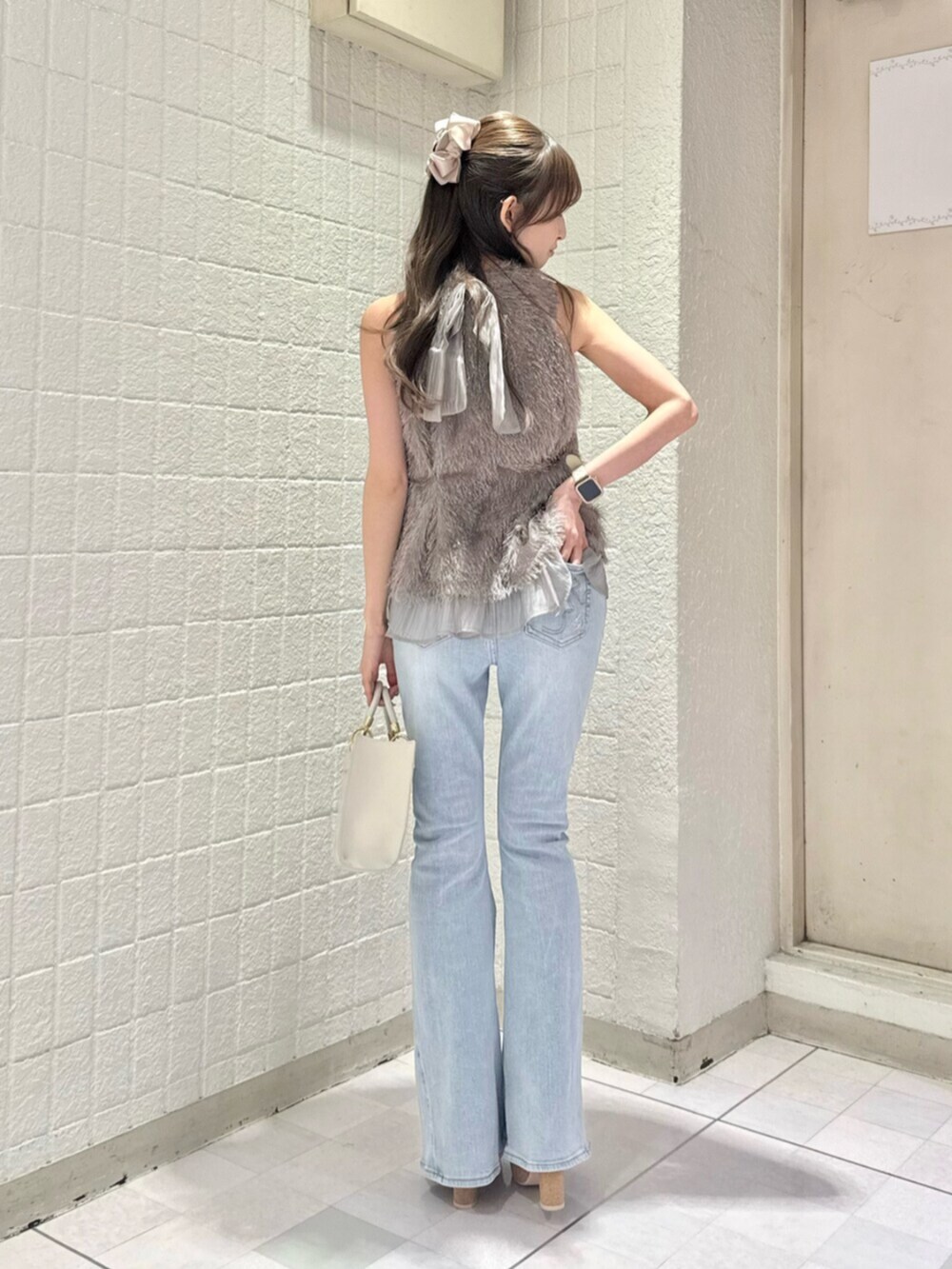 ブルー系のデニムパンツ、グレー系のタンクトップ、ホワイト系のハンドバッグを着用したレディースの夏コーディネートの4枚目の写真