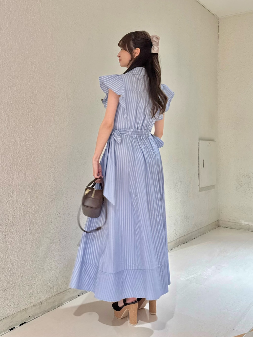 ブルー系のワンピース、ブラウン系のハンドバッグ、ブラウン系のサンダルを着用したレディースの夏コーディネートの4枚目の写真