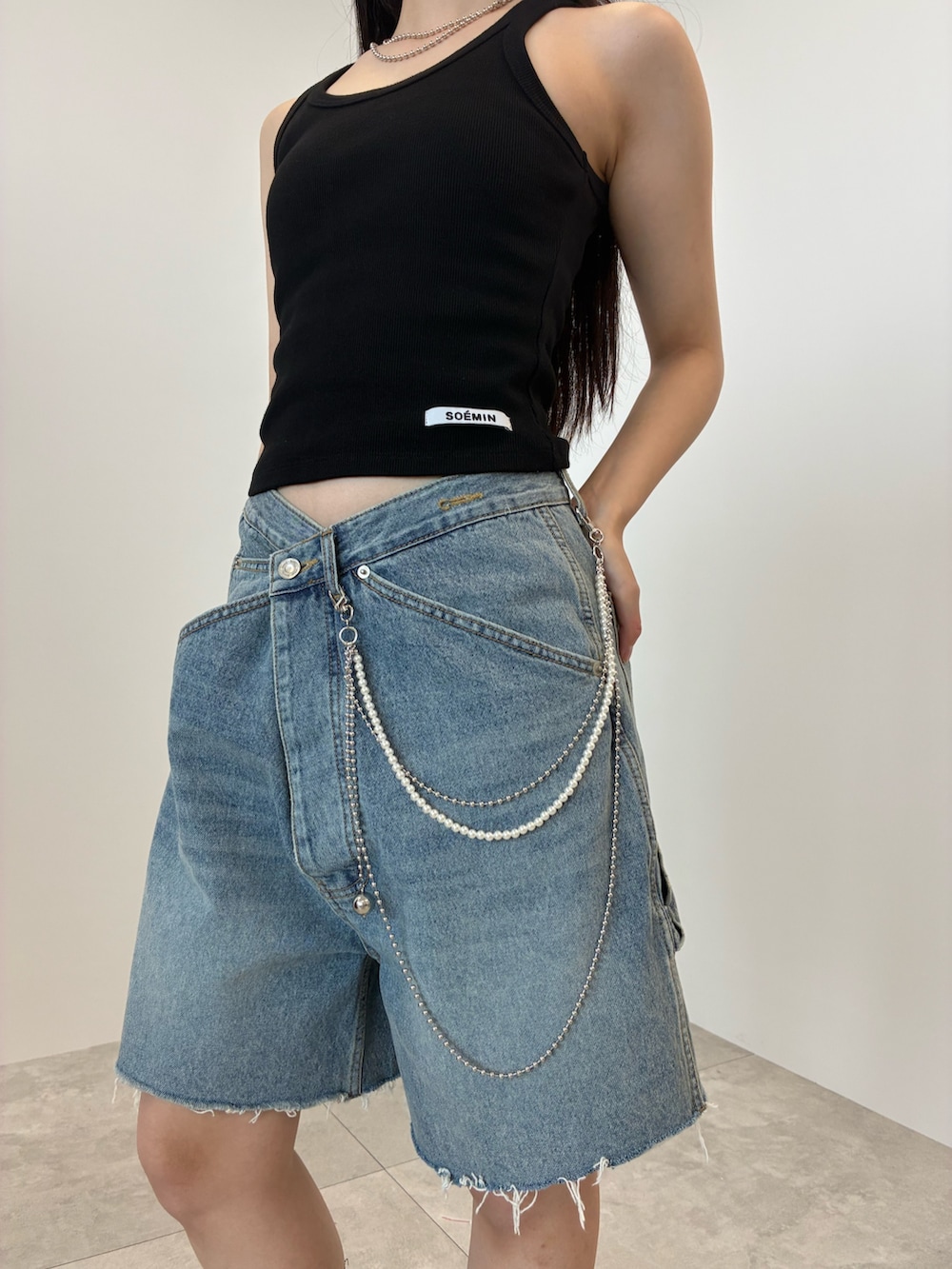ブルー系のデニムパンツ、ブラック系のタンクトップ、シルバー系のベルトを着用したレディースの夏コーディネートの4枚目の写真