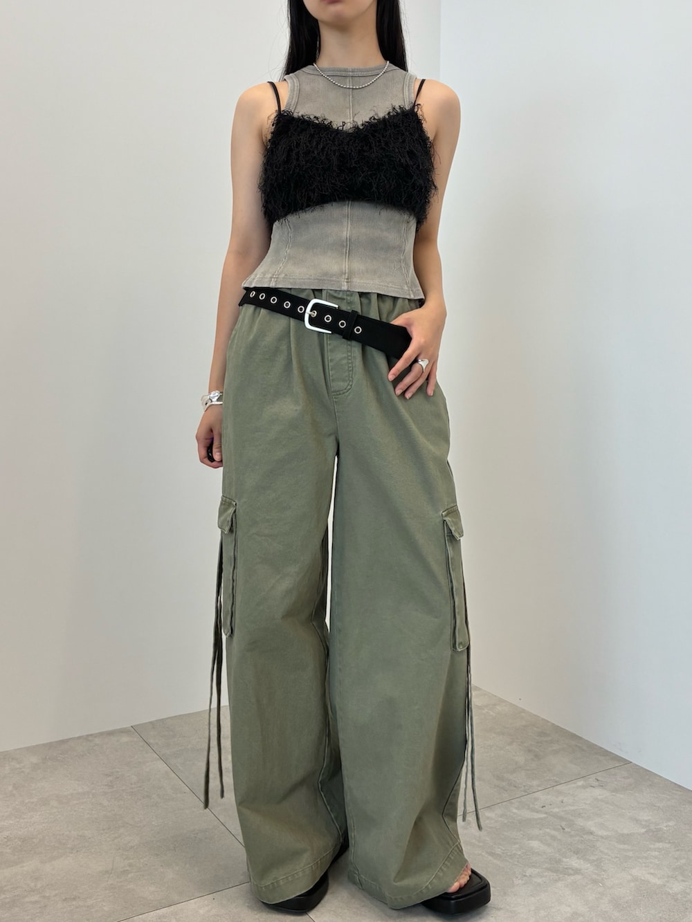 グレー系のタンクトップ、グリーン系のカーゴパンツ、シルバー系のバングル/リストバンドを着用したレディースの夏コーディネートの2枚目の写真