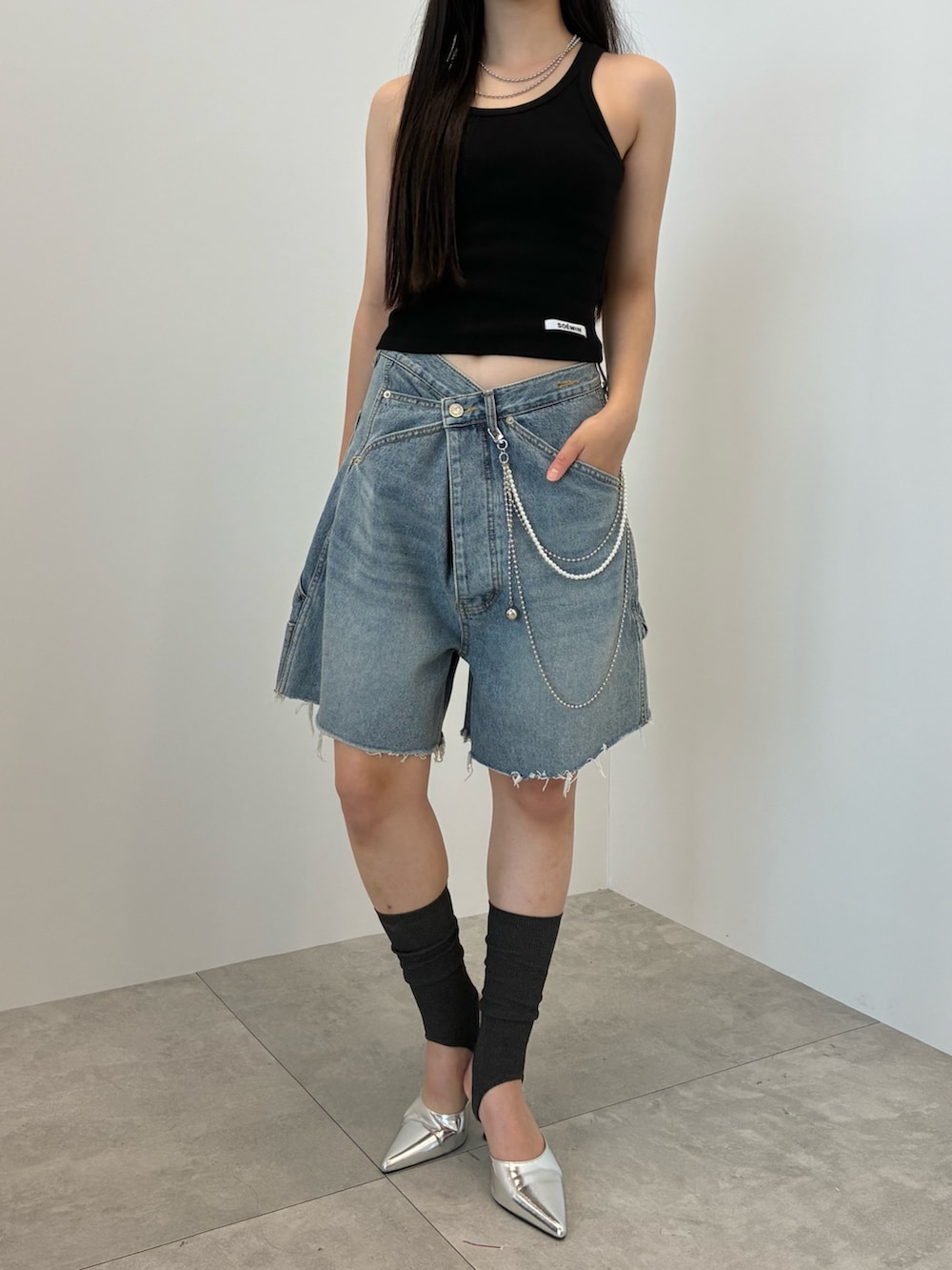 ブルー系のデニムパンツ、ブラック系のタンクトップ、シルバー系のベルトを着用したレディースの夏コーディネートの2枚目の写真