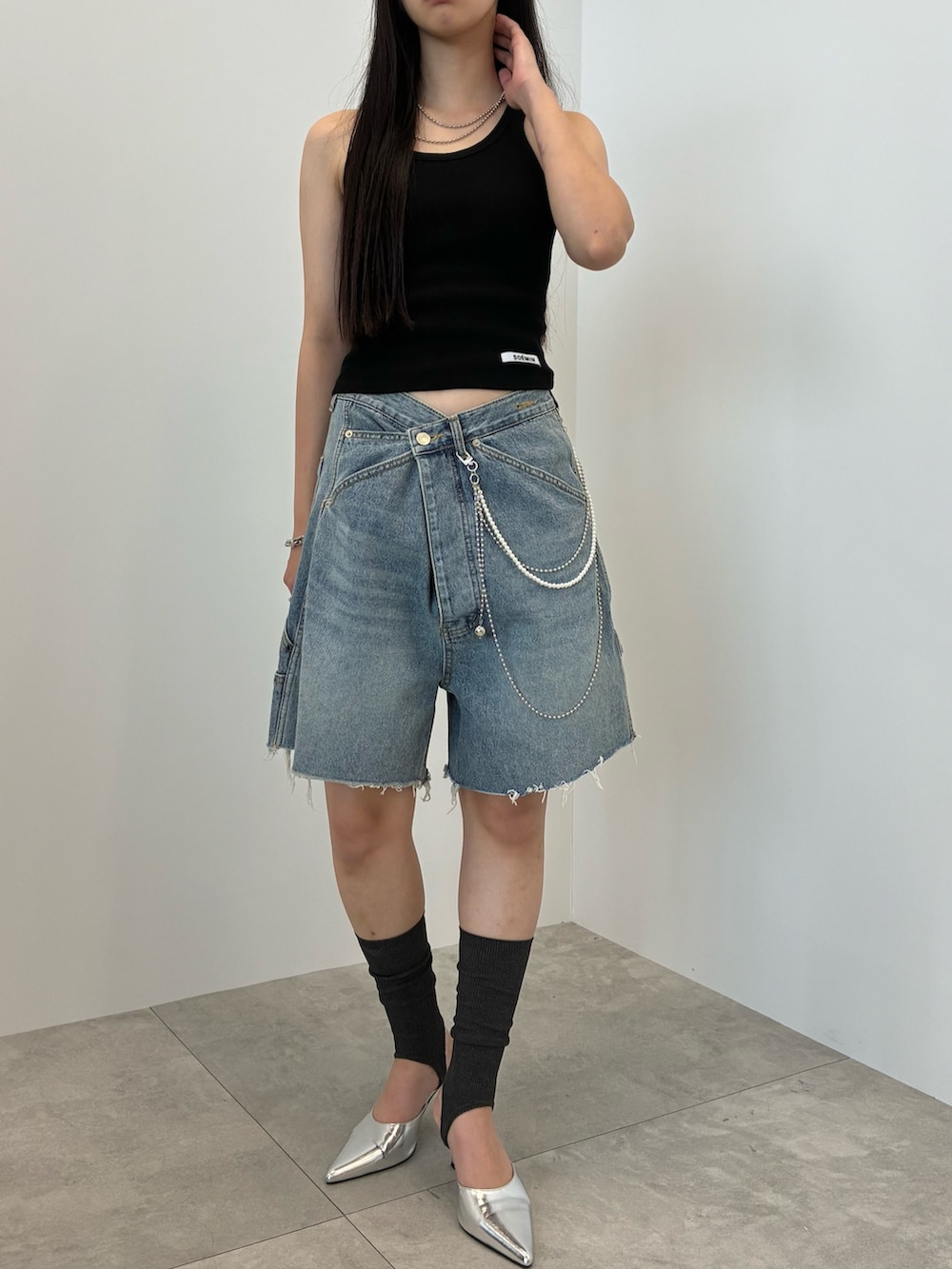 ブルー系のデニムパンツ、ブラック系のタンクトップ、シルバー系のベルトを着用したレディースの夏コーディネートの3枚目の写真