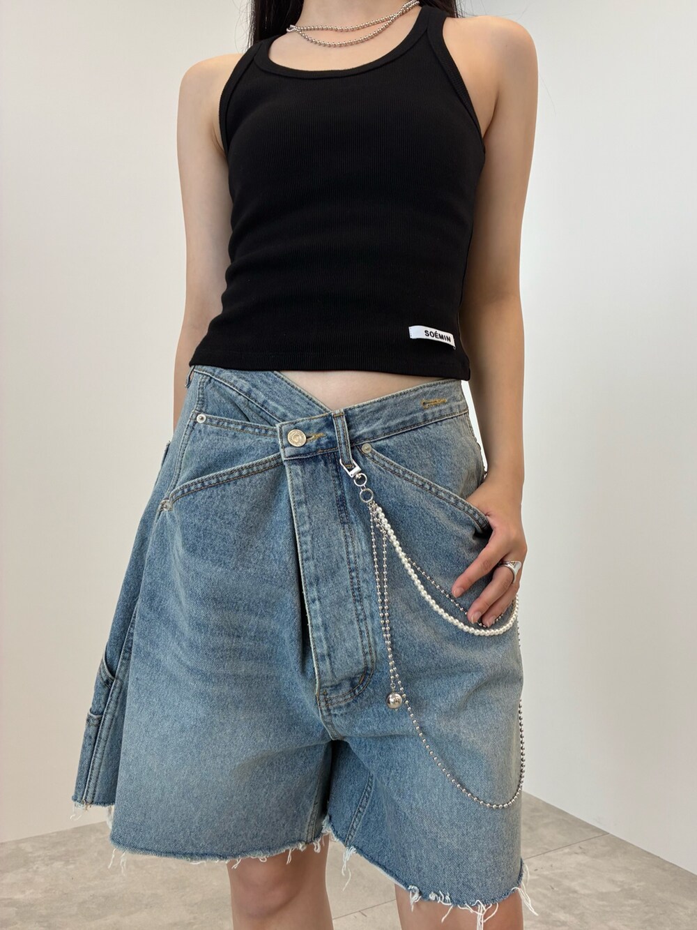ブルー系のデニムパンツ、ブラック系のタンクトップ、シルバー系のベルトを着用したレディースの夏コーディネートの5枚目の写真